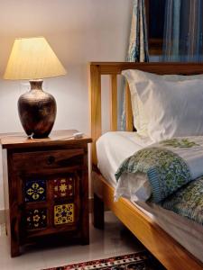 a bedroom with a bed and a lamp on a night stand at La Maison - A Boutique Bed and Breakfast in Bīr