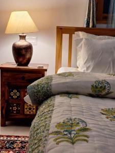 1 dormitorio con cama y mesita de noche con lámpara en La Maison - A Boutique Bed and Breakfast en Bīr