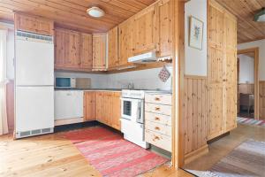 a kitchen with white appliances and wooden cabinets at Villa Franca Maria in Rättvik