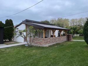 Una pequeña casa blanca con un muro de contención de ladrillo. en Apartman River, en Belišće