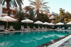 a swimming pool with white umbrellas and chairs at Sam Hotel in Antalya