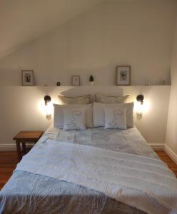1 dormitorio con 1 cama grande con sábanas y almohadas blancas en Les Hôtes Pyrénées, en Capvern