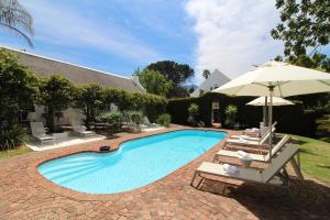 a swimming pool with two chairs and an umbrella at Rothman Manor in Swellendam