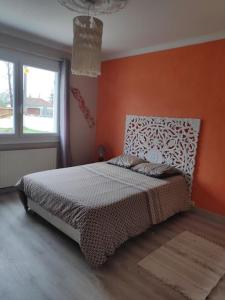 ein Schlafzimmer mit einem Bett mit einer orangefarbenen Wand in der Unterkunft Villa indépendante avec piscine in Arès