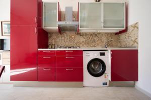eine Küche mit roten Schränken und einer Waschmaschine in der Unterkunft Trilocale San Luigi a San Vincenzo in San Vincenzo