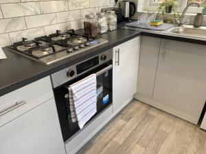 a kitchen with a stove top oven next to a sink at Stylish Home - Close to City Centre, Anfield Stadium - Free Parking in Litherland +37 photos