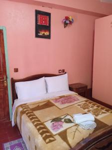 a bedroom with a large bed with pink walls at Auberge Camping Garde of Eden LE LAC in Tinerhir