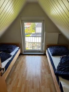 ツィングストにあるBoddenwind FW 2のベッド2台と窓が備わる屋根裏部屋です。