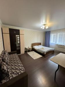 1 dormitorio con cama y sofá en Просторная квартира в жк Науаи около ТРЦ МЕГА, en Almaty