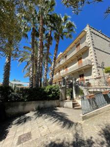 a building with palm trees in front of it at ALTA lux homeholiday stone in Modica