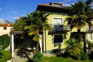 a yellow house with palm trees in front of it at Residenza Laurum B&B in Mandello del Lario