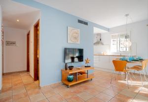 uma cozinha e sala de estar com uma mesa e uma televisão em Apartamentos Turisticos CAN CUNILL em Es Pujols