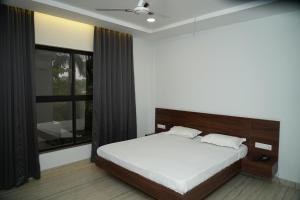ein Schlafzimmer mit einem Bett und einem großen Fenster in der Unterkunft Madhuban Garden And Resort 
