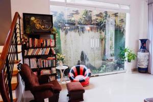 uma sala de estar com uma estante de livros e uma cadeira em Rose's House Hue em Hue