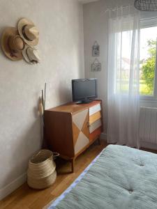 a room with a television on a dresser with a window at Chambre avec petit dej à 2kms du centre de Nevers in Varennes Vauzelles