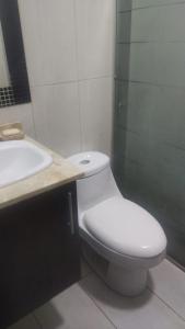 y baño con aseo blanco y lavamanos. en Suite ICON, en Quito