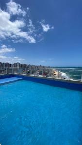 a large blue swimming pool with a view of the beach at Smart Studio in Salvador