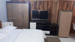 1 dormitorio con 1 cama y TV de pantalla plana en Casa Jardim de Gramado, en Gramado
