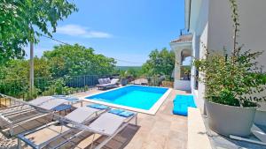 a swimming pool in a yard with chairs and a pool at Luxury apartment Viktorija with private pool in Čižići