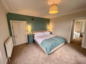 um quarto com uma cama e uma parede verde em St Marys Farmhouse - Traditional Country Farmhouse with Open Fire em Fochabers