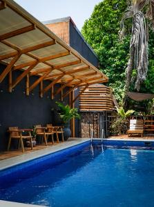 a swimming pool with a wooden pergola next to a house at La Flor de Coco in Sámara