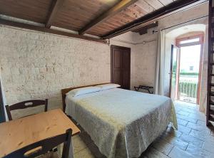 a bedroom with a bed and a table and a window at Tipico Resort in Alberobello