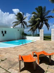 einen Pool mit zwei Orangenstühlen und Palmen in der Unterkunft NUMAR HOTEL in João Pessoa