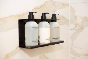 a shelf with four shampoo bottles on a wall at Anegang Boutique Hotel in Haarlem