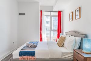 1 dormitorio con 1 cama y una ventana con cortinas rojas en Dan Leckie Apartments, en Toronto