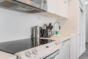 cocina blanca con fogones y fregadero en Dan Leckie Apartments, en Toronto