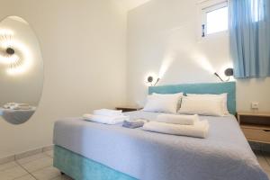 a bedroom with a blue bed with towels on it at Tropical Beach "Triton" in Petalidhion