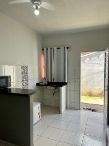uma cozinha com pisos em azulejo branco e uma grande janela em Casa da Vó Maria! Studio 08 em Goiânia
