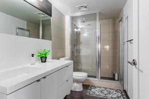 a white bathroom with a toilet and a shower at 300 Front Suites in Toronto