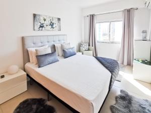 a bedroom with a large white bed with blue pillows at Apartment Panorama Rocha Capri in Portimão