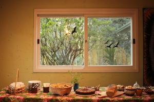 - une table avec de la nourriture et une fenêtre dans l'établissement Casa colonial aconchegante compartilhada, à Três Coroas