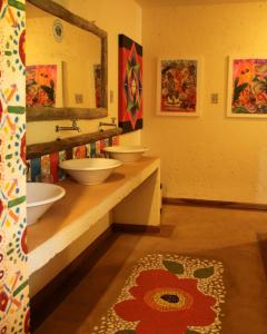 La salle de bains est pourvue de 2 lavabos, d'un miroir et d'un tapis. dans l'établissement Casa colonial aconchegante compartilhada, à Três Coroas