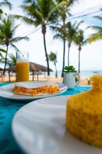 uma mesa com um prato de comida e um copo de sumo de laranja em Apprezzare . Pousada beira-mar em Porto de Galinhas