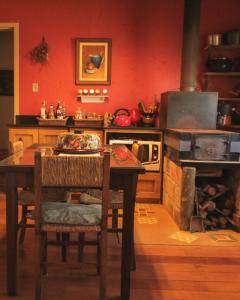 Il comprend une cuisine équipée d'une table et d'un four avec une table et des chaises. dans l'établissement Casa colonial aconchegante compartilhada, à Três Coroas