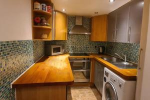 La cuisine est équipée de placards en bois, d'un évier et d'un lave-vaisselle. dans l'établissement Boutique Studio Flat in Notting Hill Gate, à Londres