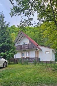 una casa blanca con terraza y un coche delante en Cabana 2 Râuri, en Bratca