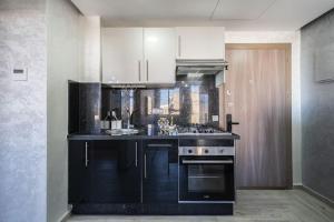 a kitchen with black counters and white cabinets at Stylish Studio à Ain Sebaa in Casablanca