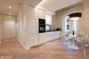 une cuisine avec des armoires blanches et une table avec des chaises dans l'établissement Dolce Vita Apartament, à Florence