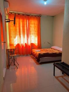 um quarto com 2 camas e uma cortina laranja em Hotel las Acacias Hospedajes en Nueva Loja em Nueva Loja
