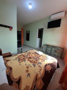 - une chambre avec un grand lit et une couverture fleurie dans l'établissement Hotel las Acacias Hospedajes en Nueva Loja, à Nueva Loja