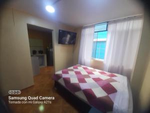 ein Schlafzimmer mit einem Bett mit einer karierten Decke in der Unterkunft Kely 6 Apartamento 2do Piso in Lima