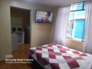 ein Schlafzimmer mit einem Bett und einem TV an der Wand in der Unterkunft Kely 6 Apartamento 2do Piso in Lima