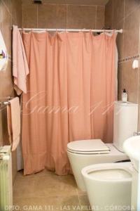 a bathroom with a pink shower curtain and a toilet at Departamento GAMA 111. in Las Varillas +17 photos
