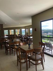 a dining room with tables and chairs and windows at Pousada Da Serra in Bananeiras
