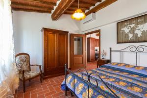1 dormitorio con 1 cama y 1 silla en San Lorenzo Agriturismo en Buonconvento