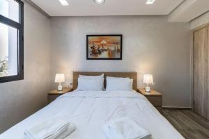 1 dormitorio con 1 cama blanca grande y 2 lámparas en Chic Apartment Cosy Stay, en Casablanca